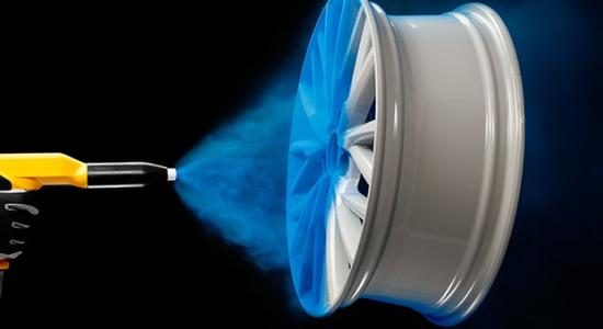 Spray gun applying blue powder coating to a wheel